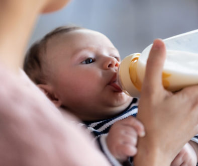 Mother feeding her baby son with feeding bottle while sitting on