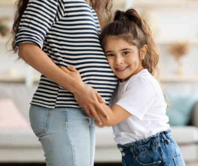 Cute little girl hugging her pregnant mother big belly